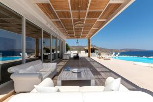 an outdoor living room with white furniture and a pool at Alegria Mykonos 7 Suites in Kalafatis