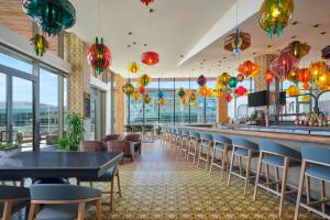 a restaurant with a long bar with chairs and lights at The Alexander, Autograph Collection in Indianapolis