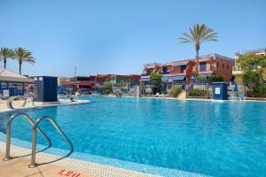 a large blue swimming pool with palm trees and buildings at Free Airport Shuttle and Parking in San Bartolomé