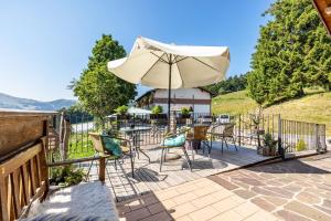a patio with a table and chairs and an umbrella at Agritur El Casel in Brentonico