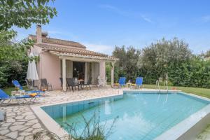 a swimming pool with chairs and a house at Villa Fotini Lefkada in Lefkada