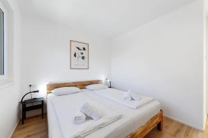 a white bedroom with a bed with white sheets and towels at Apartment Mountain Suite in Naturno