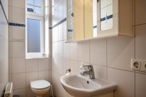 a bathroom with a sink and a toilet and a window at Haus Übersee Wohnung Fidji in Travemünde +19 photos