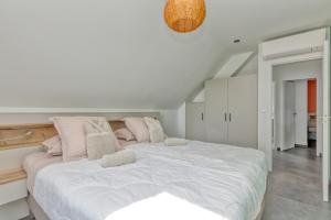 a white bedroom with a large bed with pink pillows at Villa Ker Minet - Houat - 8 pers in Piriac-sur-Mer +19 photos
