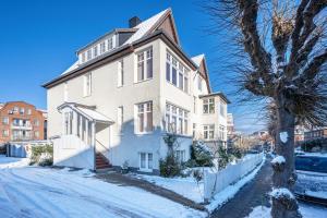 a large white house on a snowy street at Haus Übersee Wohnung Fidji in Travemünde