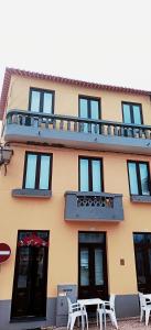 a building with a balcony and tables in front of it at Valley Apartamentos T1 in Vila Nova de Foz Coa