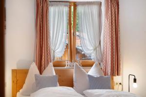 a bedroom with a bed with white pillows and a window at Ferienwohnung Zugspitze in Grainau