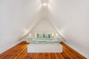a bed in a room with white walls and wooden floors at Alte Seifensiederei 2 in Stralsund