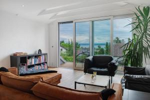 a living room with leather furniture and a large window at Aussichtsreich Am See in Uhldingen-Mühlhofen