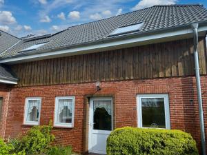 a red brick house with a white door at Gaestehaus Nuke in Langeneß