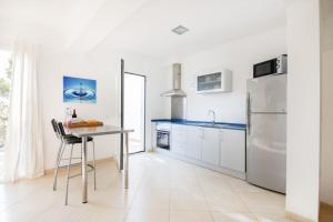 a white kitchen with a table and a refrigerator at Mestral in Port de Soller
