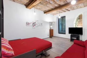 a living room with a red bed and a flat screen tv at La Sartoria in Porlezza
