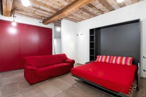 a red couch in a room with a red wall at La Sartoria in Porlezza
