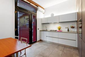 a kitchen with white cabinets and a wooden table at La Sartoria in Porlezza +14 photos