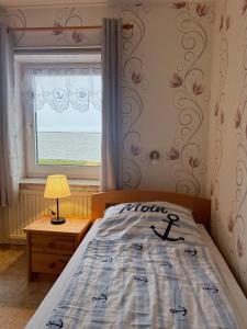 a bedroom with a bed and a window with the ocean at Gaestehaus Nuke in Langeneß