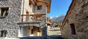 a stone building with a clock on a balcony at Appartement ô Canton in Val Cenis