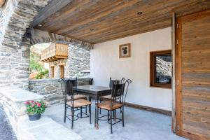 a table and chairs on a patio with a stone wall at Appartement ô Canton in Val Cenis