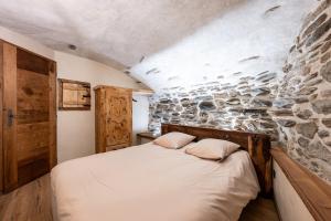 a bed in a room with a stone wall at Appartement ô Canton in Val Cenis