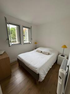 a bedroom with a large bed and two windows at Plage du Couchant in La Grande Motte