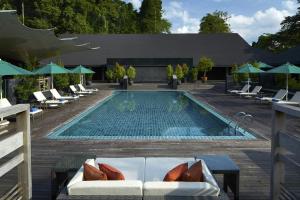 a swimming pool with chairs and a couch and a table at Mulu Marriott Resort in Mulu