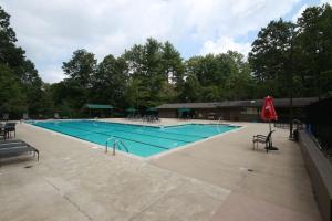 a large swimming pool with chairs and a red umbrella at Hummingbird Hideaway · Hummingbird Hideaway in Connestee Falls in Brevard