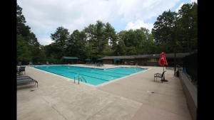 a large swimming pool with chairs and a red umbrella at Shady Creek Cabin · Shady Creek Cabin in Connestee Falls with s in Brevard