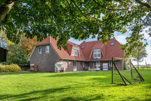 a house with a red roof on a green lawn at Haus Deichgraf in Nordstrand