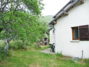 a white house with a window and a chair in a yard at Gîte le Suquet - en pleine nature in Dourbies