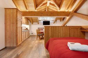 a bedroom with a red bed and a kitchen at Aux Pieds du Malatra' 1 in Saint-Rhémy-en-bosses