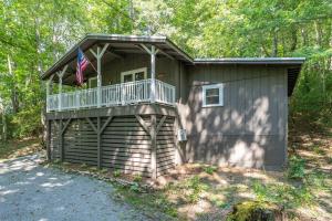 a house with a balcony and an american flag at The Deep Forest Green Cottage · The Deep Forest Green Cottage in Cedar Mountain