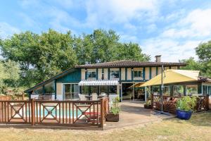a house with a deck and an umbrella at Espace, calme, confort in Saint-Michel-Escalus