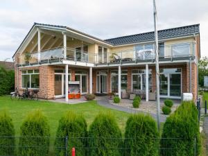 a brick house with a balcony on a lawn at Haus Eiderblick in Horst