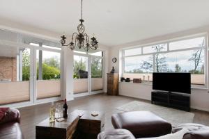 a living room with a television and large windows at Haus Eiderblick in Horst