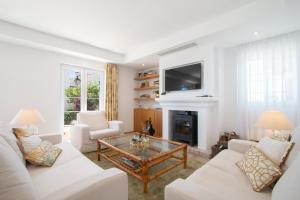 a living room with white furniture and a fireplace at Townhouse El Naranjal in Marbella