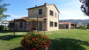 a house with a flower bush in front of it at La Valle Del Sole - Val D'Orcia in Castiglione dʼOrcia