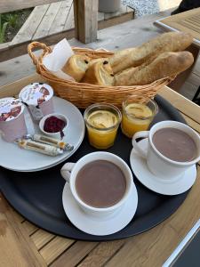 a tray with two cups of coffee and a basket of bread at La Baïta De La Foux in La Foux d'Allos