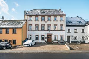 a large white house with cars parked in front of it at Die Residenz in Neidenbach
