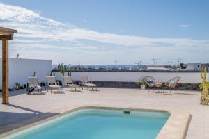 a swimming pool on a patio with chairs and a table at Villa Esmeralda in Lanzarote