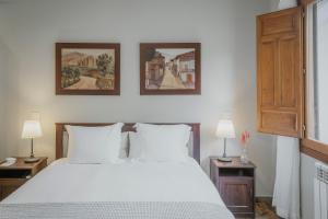 a bedroom with a white bed and two pictures on the wall at Finca El Aguilojo in Mombeltrán