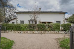 a large white house with a stone fence in front of it at Finca El Aguilojo in Mombeltrán