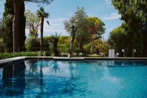 a blue swimming pool with trees in the background at Al segnavento Montese in Toscolano Maderno