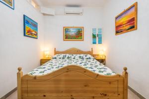 a bedroom with a wooden bed and paintings on the wall at Casa San Fruttuoso in Carloforte