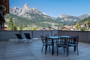 a table and chairs on a balcony with mountains at Buffaure a parte in Pozza di Fassa