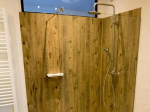 a bathroom with a shower with a wooden wall at Ferienwohnung Maulbetsch in Alpirsbach +8 photos