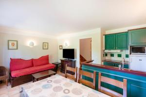 a living room with a red couch and a kitchen at Domaine de Pinsolle in Soustons