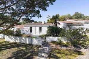 a white house with a fence in front of it at Ile de Noirmoutier - Maison T4 in La Guérinière