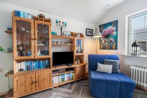 a living room with a tv and a blue chair at Ferienwohnung am Töschenbach in Hennstedt