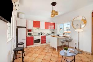 a kitchen with red cabinets and a table and chairs at A Casa de Emy in Cabanas de Tavira