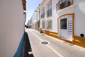 a narrow street with a white and yellow building at A Casa de Emy in Cabanas de Tavira