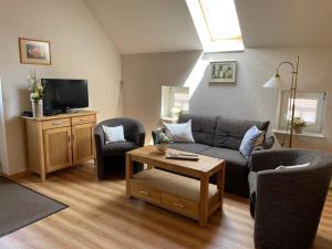 a living room with a couch and chairs and a tv at Uhlenhoff Boyken in Bokellerostermoor